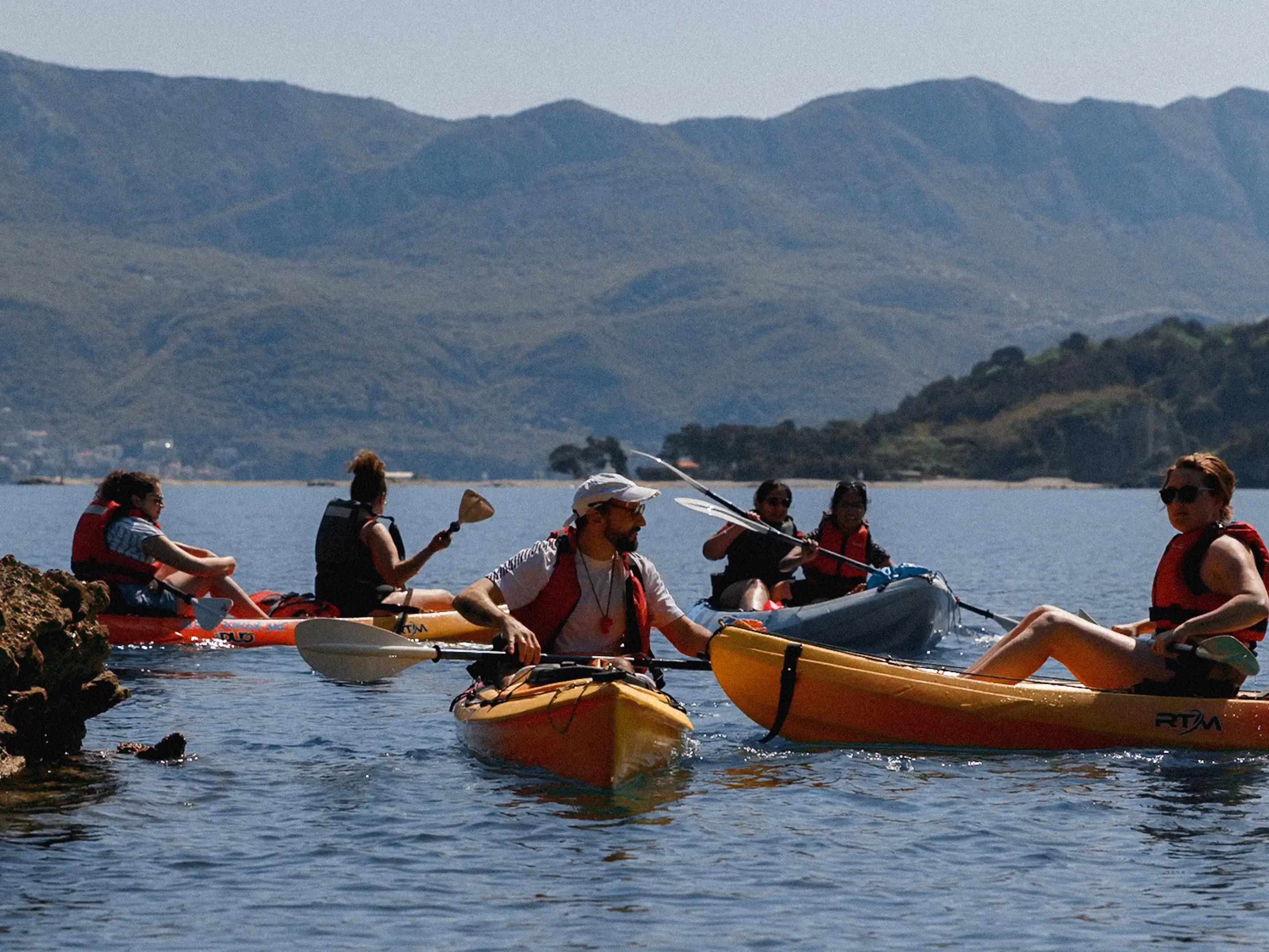 Sea kayaking group resting on calm Adriatic water with Montenegro mountains in the background