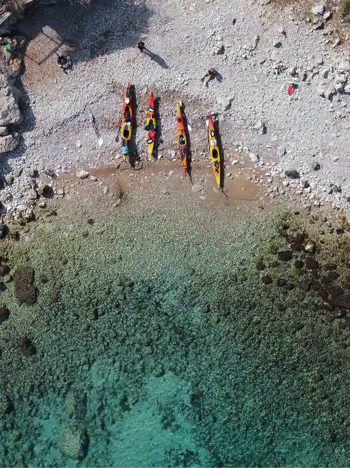 sea kayaks lined up on a clear Adriatic beach in Montenegro, aerial view