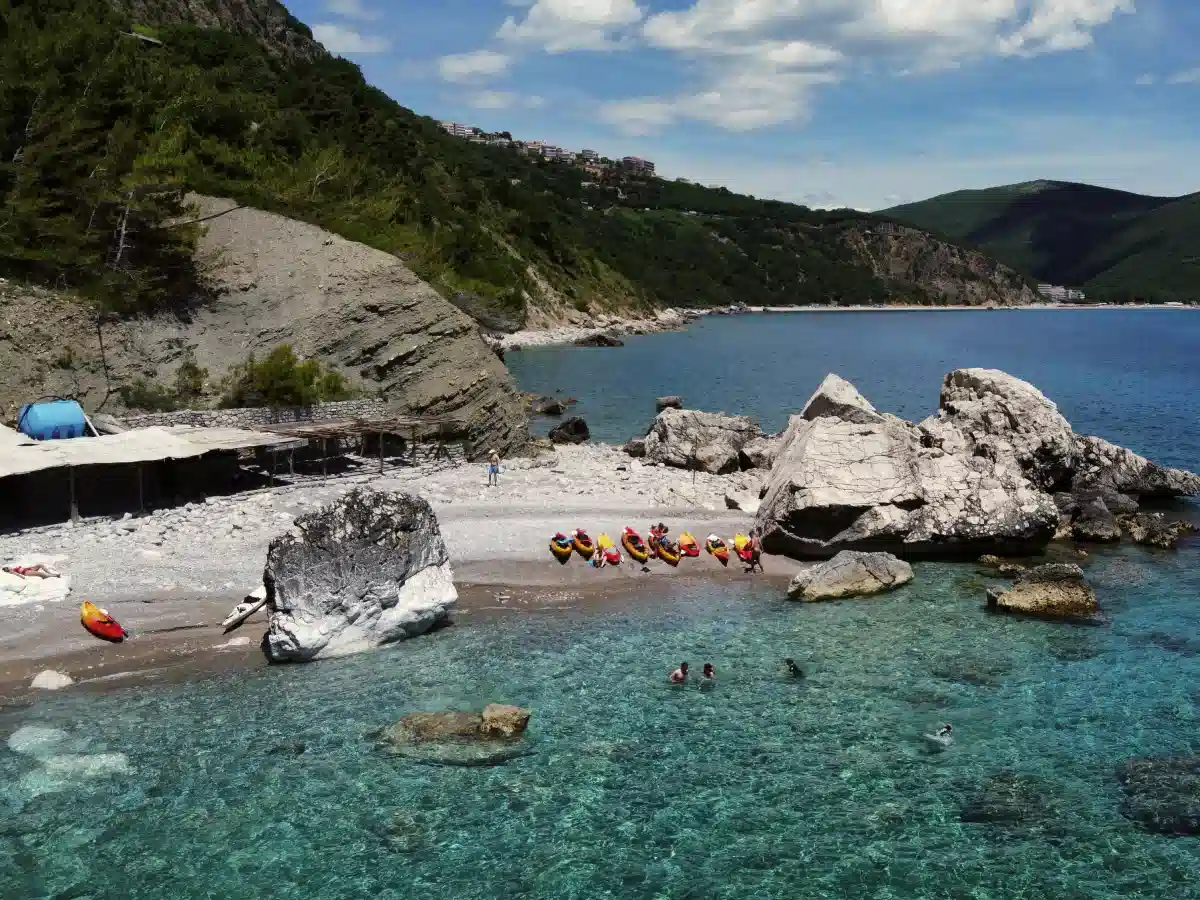 Secluded Montenegrin beach with kayaks on the shore and swimmers in clear turquoise water