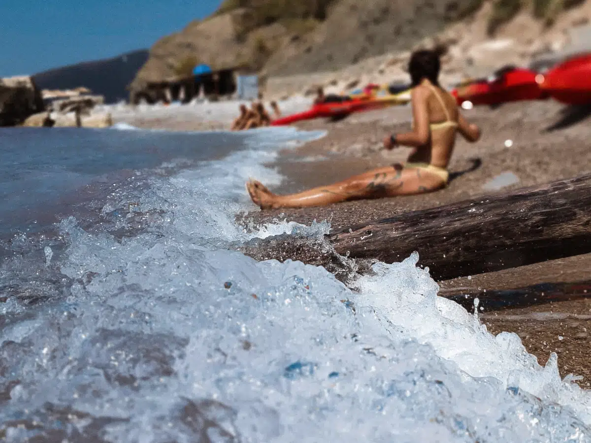 Woman relaxing on a rocky beach with kayaks lined up by the shoreline