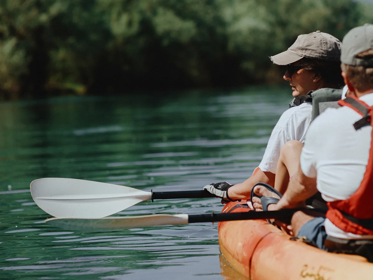 Close-up of kayak paddlers with white blades skimming emerald water