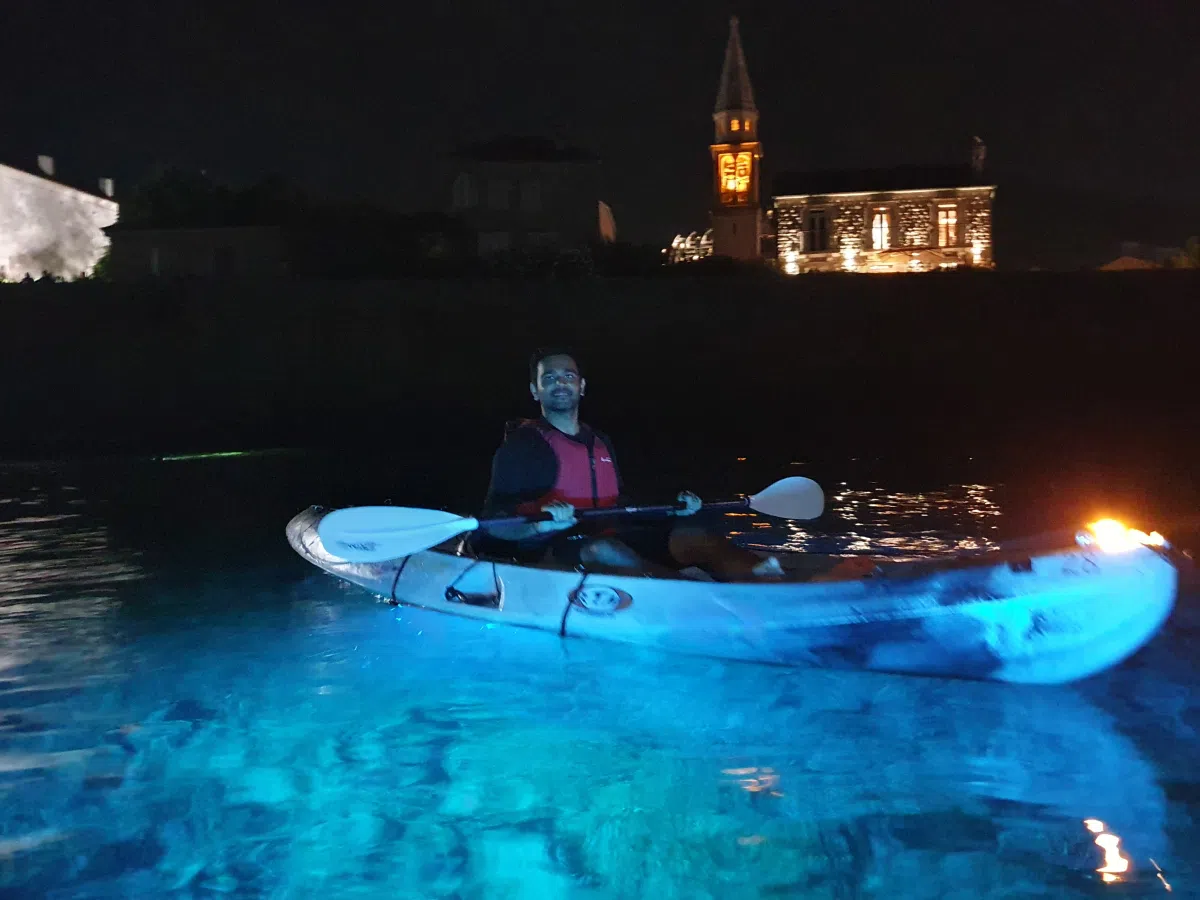 LED kayak illuminating turquoise water in front of Budva’s church tower