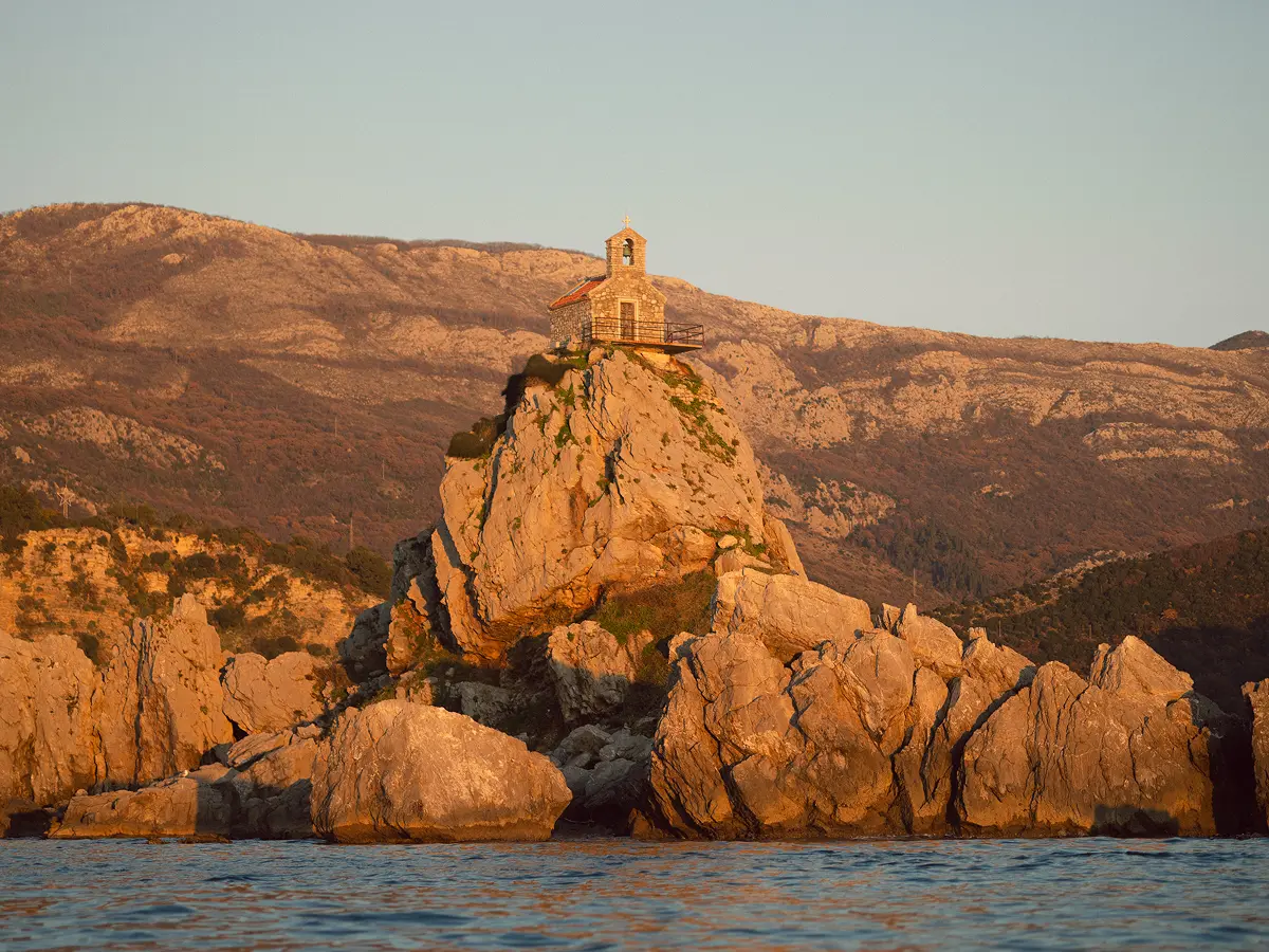 Small stone chapel perched on a rocky islet at golden hour