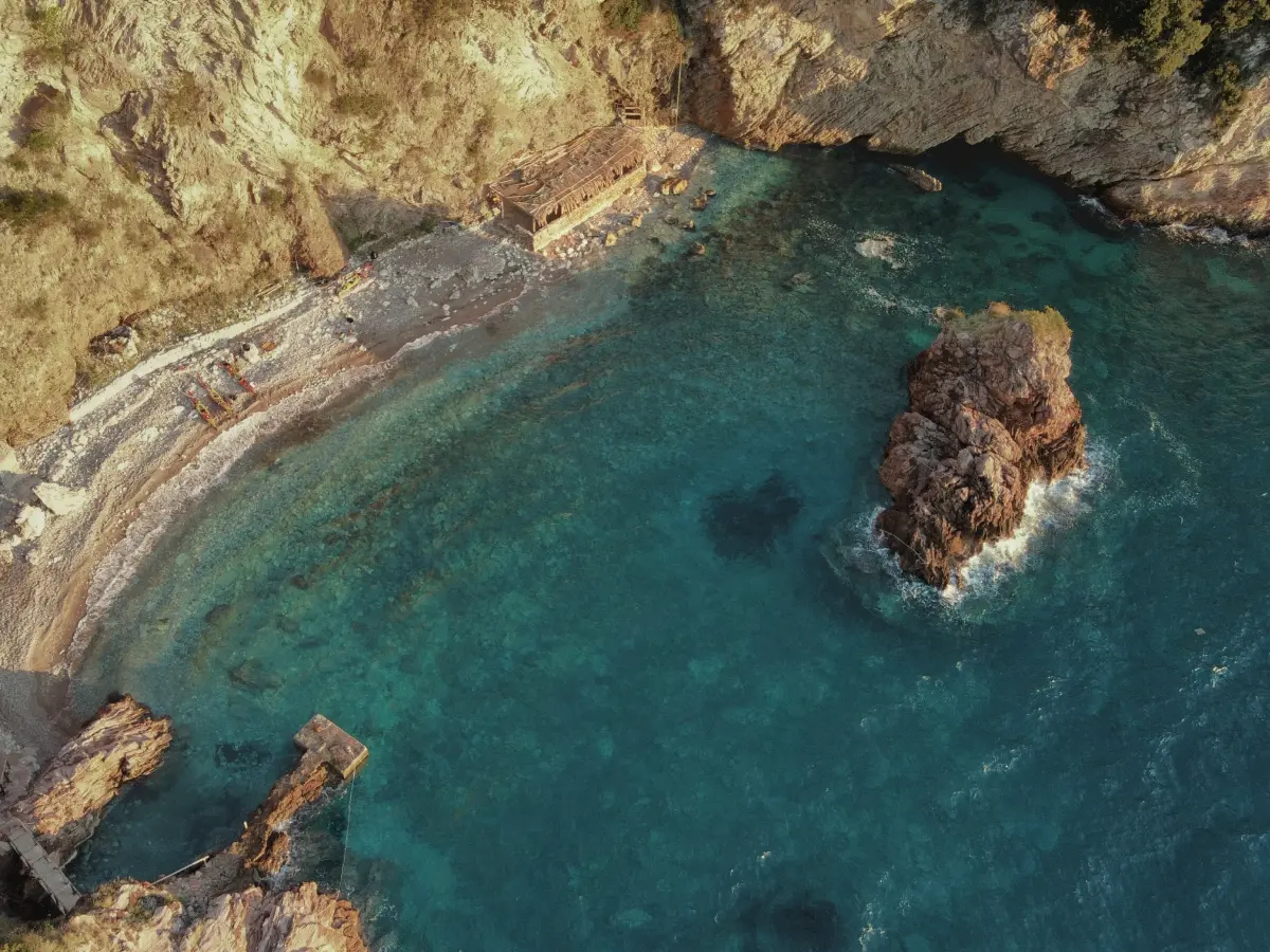 Aerial view of a secluded cove with clear turquoise water and rocky shore