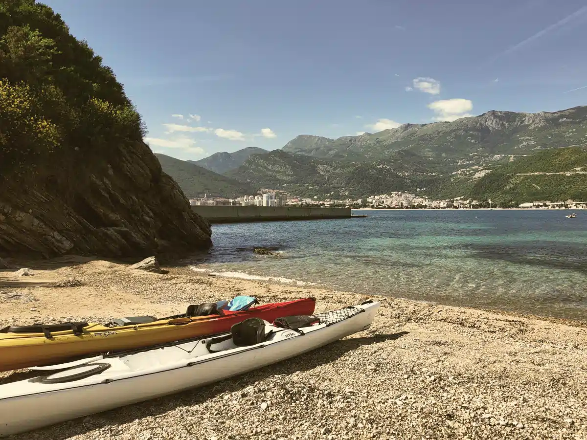 Sea kayaks on a pebble beach with Budva Bay and mountains — Sveti Nikola Island