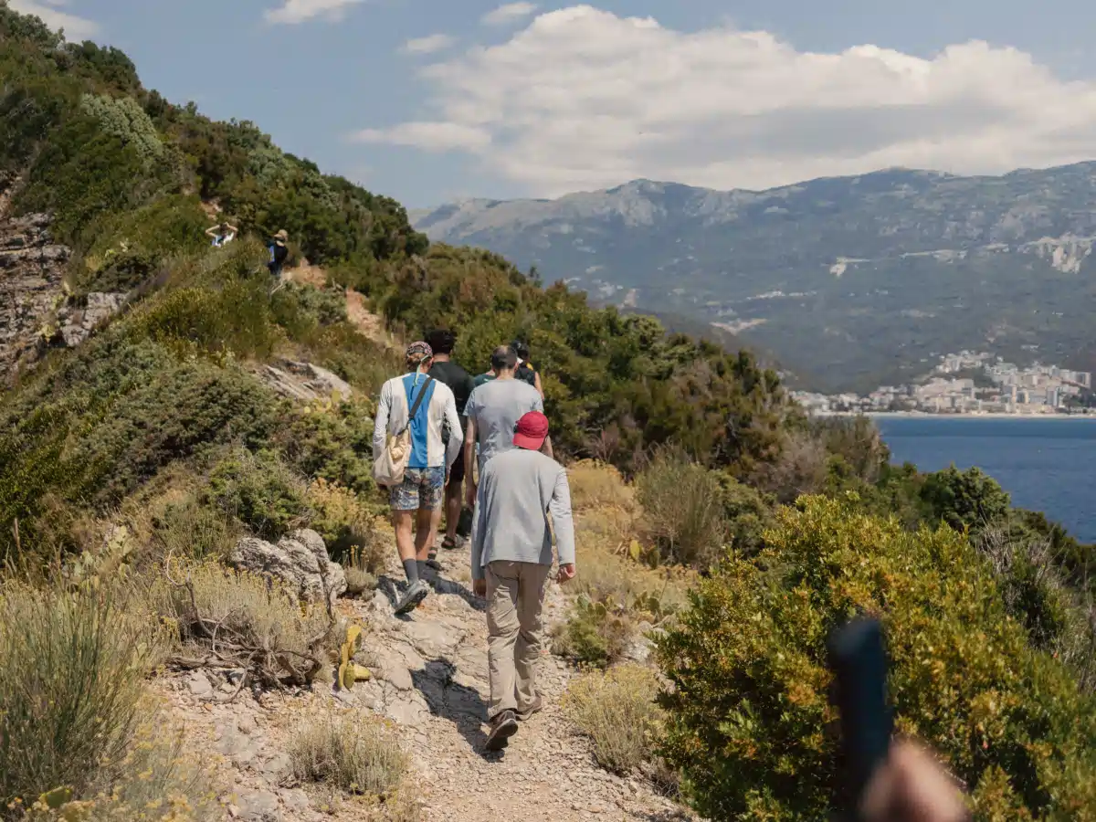 Group on a cliff-top path overlooking Budva Bay and surrounding mountains