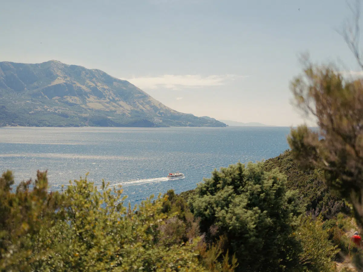 Adriatic seascape from Sveti Nikola Island with a tour boat wake below the headland