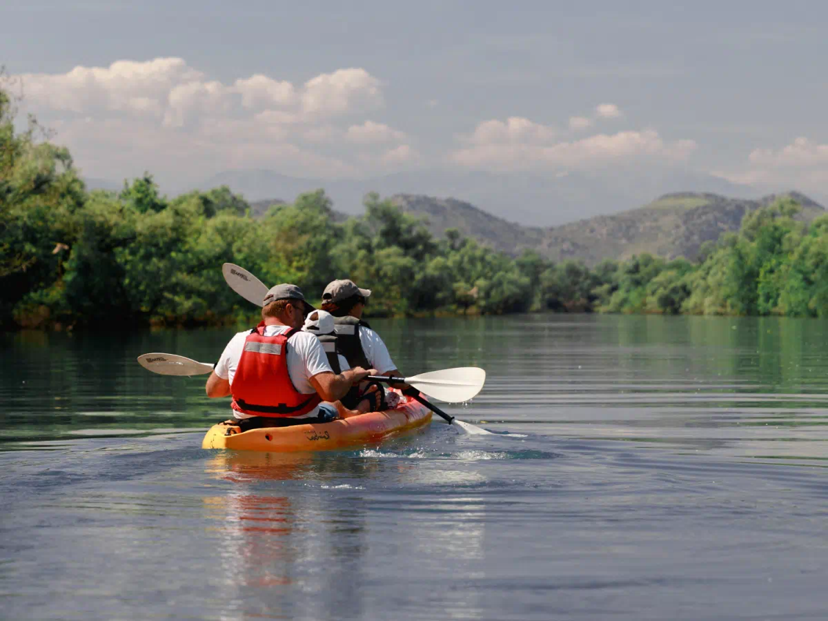 Paddlers on calm Skadar Lake water with mountains in the background